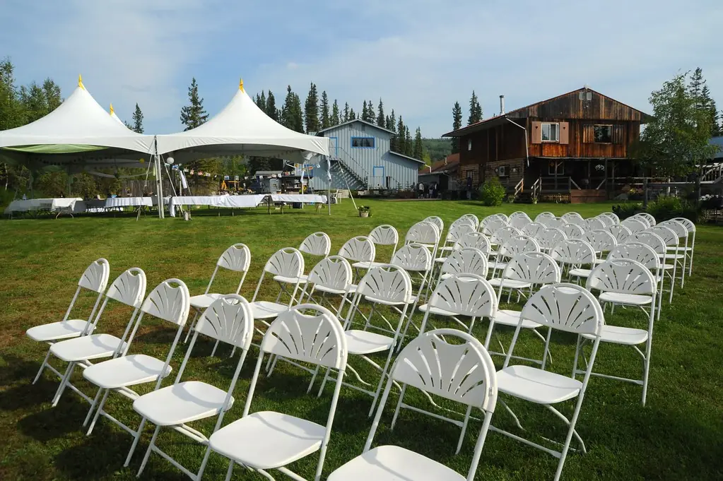White peaked tents and rows of folding chairs on a lawn